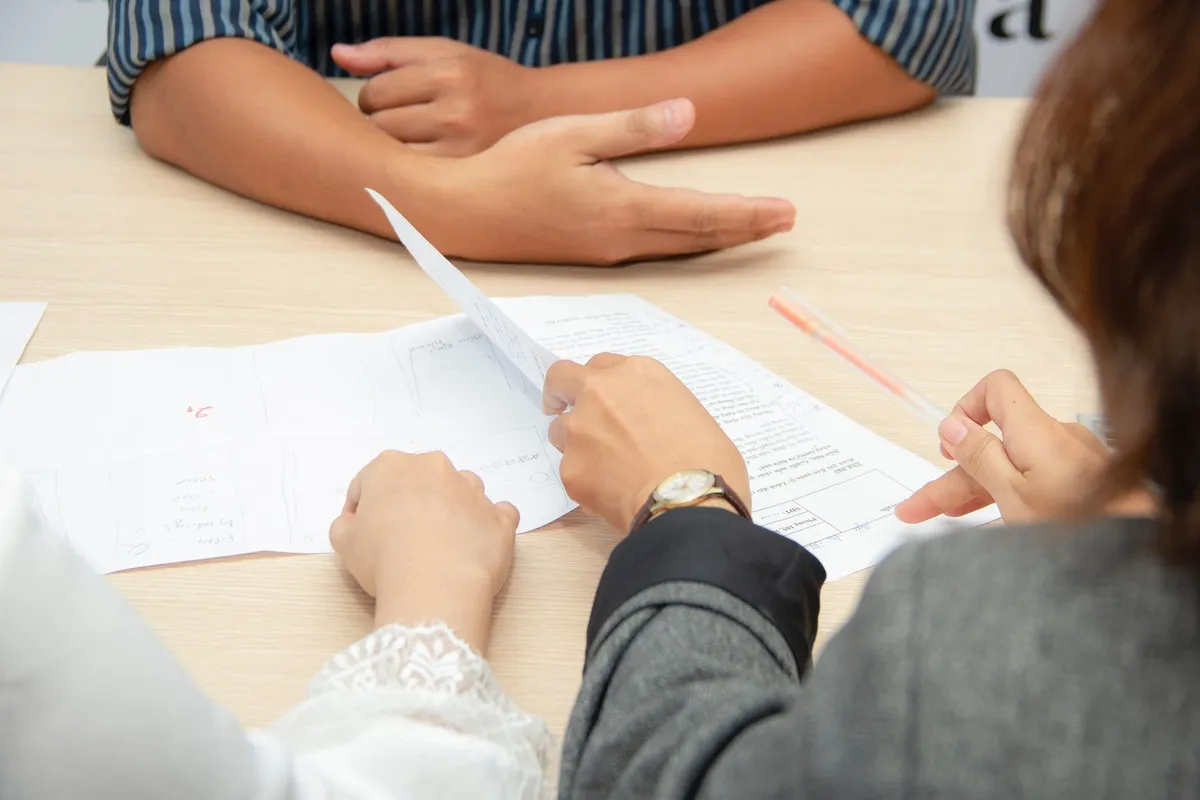 Zwei Personen unterschreiben Unterlagen am Tisch